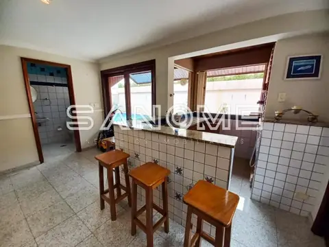 Cozinha com balcão, banquetas e janelas