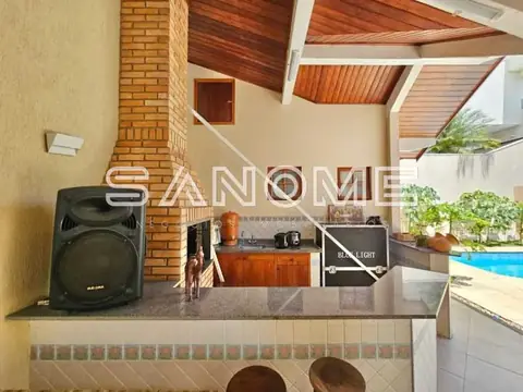 Área de lazer com cozinha e piscina ao fundo
