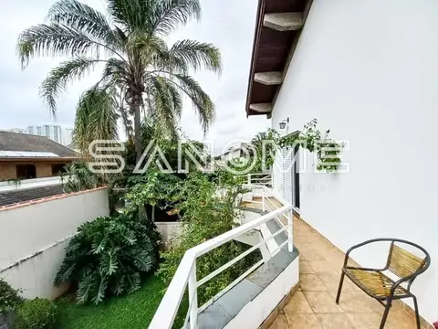 Varanda com piso de madeira e vista para jardim com palmeira