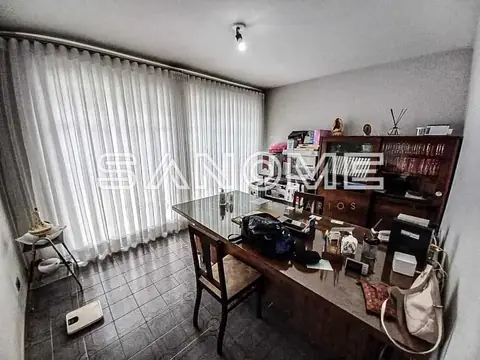 Escritório com mesa, estantes e cortinas verticais