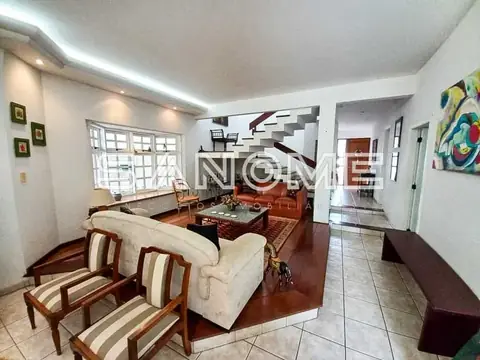 Sala de estar com sofá, poltronas e escada ao fundo