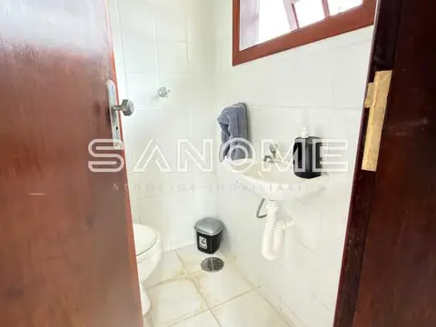 Banheiro com azulejos brancos e porta de madeira