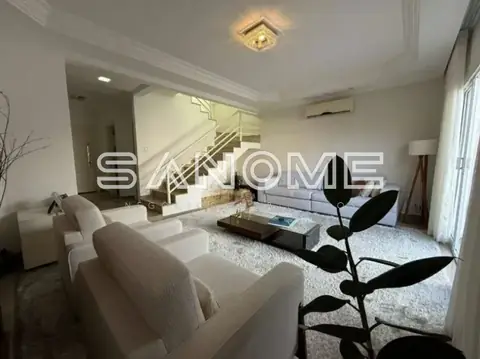 Sala de estar com sofá, escada e pé direito duplo