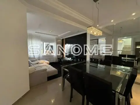 Sala de jantar com mesa preta e sala de estar ao fundo