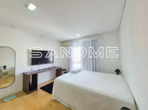 Quarto com cama, escrivaninha e televisão