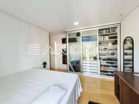 Quarto com cama, guarda-roupa espelhado e piso em madeira