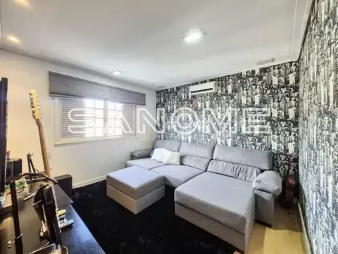 Sala com sofá cinza e parede de fotos em preto e branco