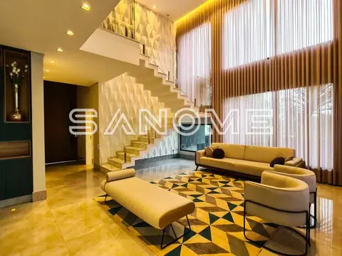 Sala de estar com sofás, escada e pé direito duplo