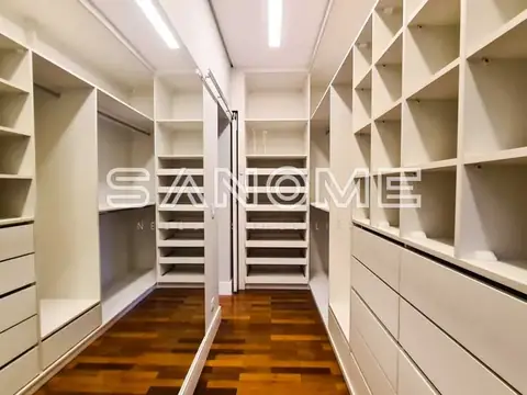 Closet amplo com prateleiras brancas e piso em madeira