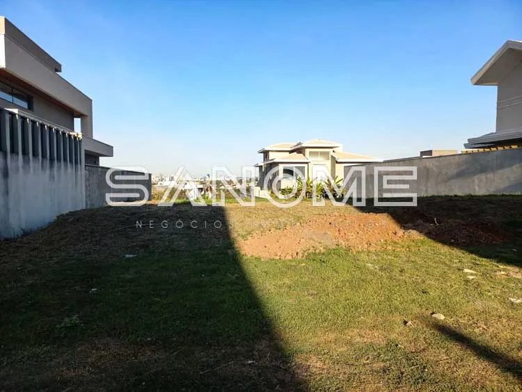 Terreno com grama e construções ao fundo