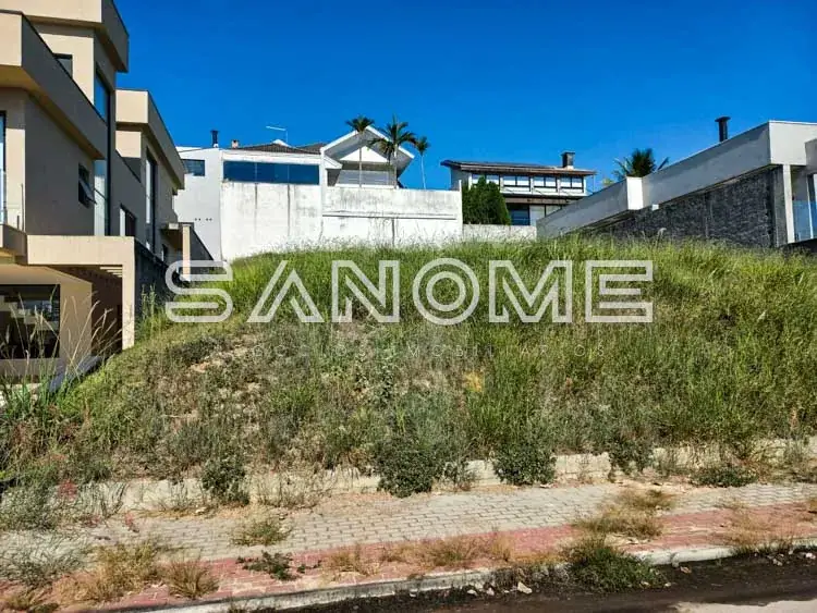 Terreno com vegetação e casarões ao fundo