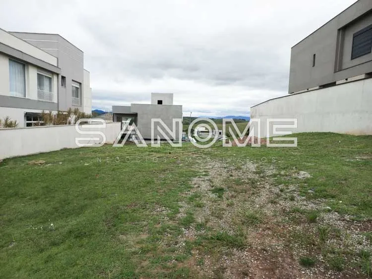 Terreno com casarões ao fundo e cerca branca