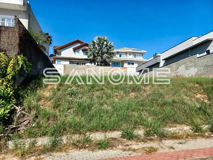 Terreno baldio com muro e casarões ao fundo