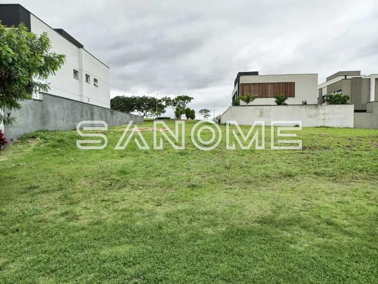 Terreno plano com grama e casarões ao fundo