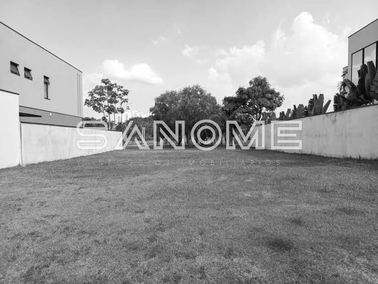 Terreno vazio com muro e construções ao fundo