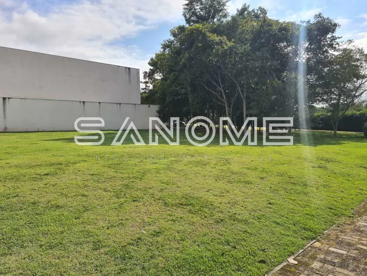 Terreno com gramado, árvores e construção ao fundo