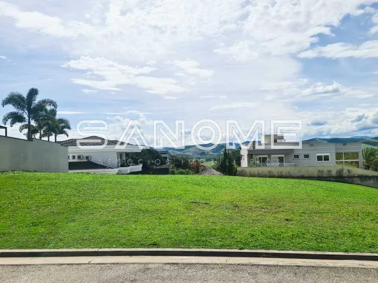 Terreno com grama verde e casarões ao fundo