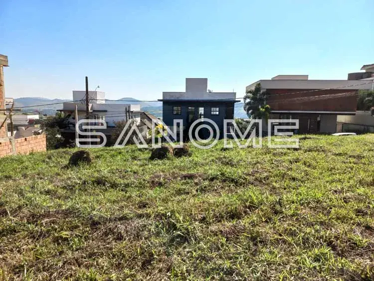 Terreno com casa azul e construções ao fundo