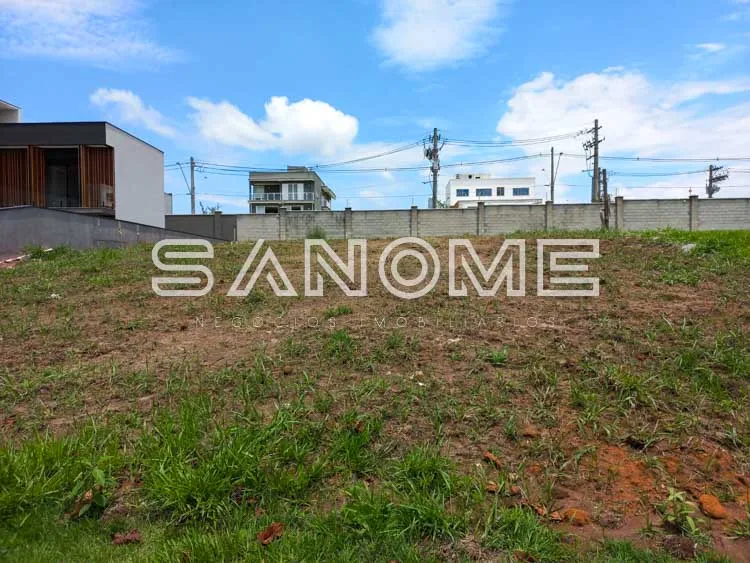 Terreno com placa de sinalização e casarões ao fundo
