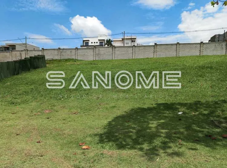 Terreno cercado com grama e construções ao fundo