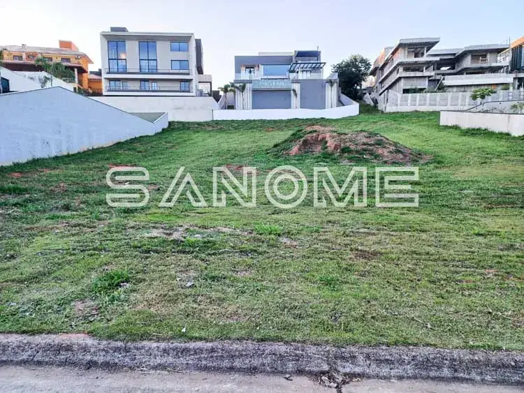 Terreno com grama e casarões ao fundo