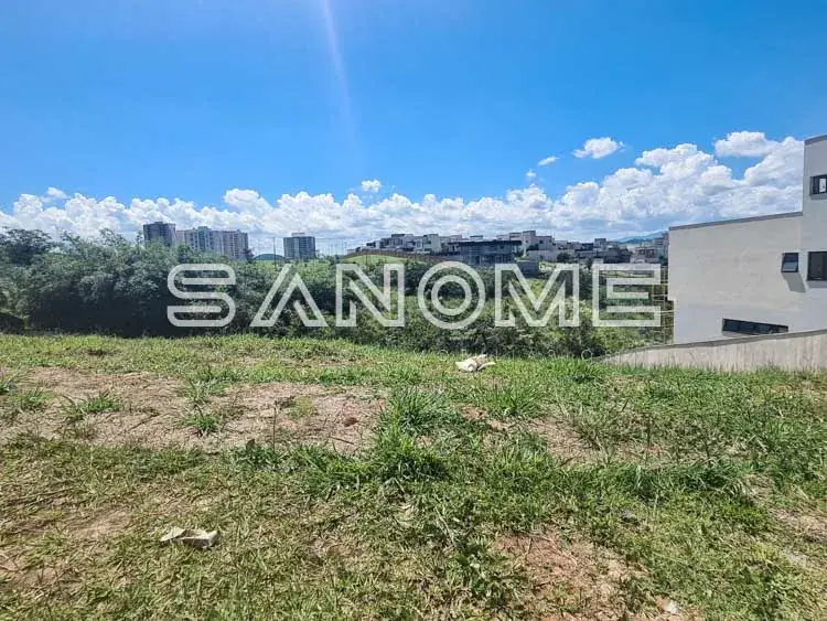 Terreno vazio com grama e construção ao fundo