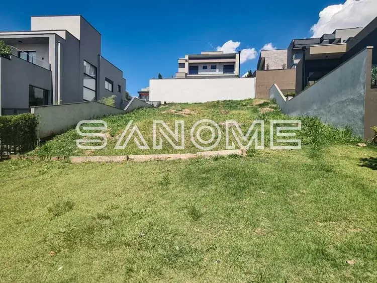 Terreno com grama e casarões ao fundo