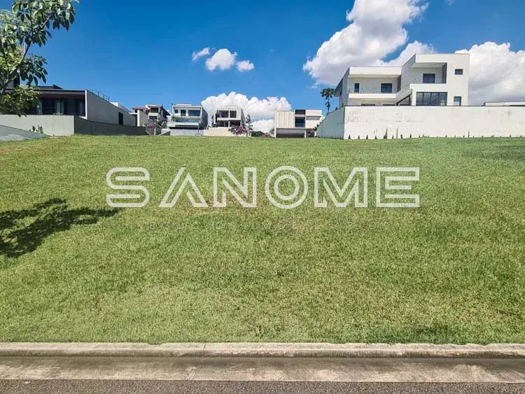 Terreno com casarões ao fundo e céu azul