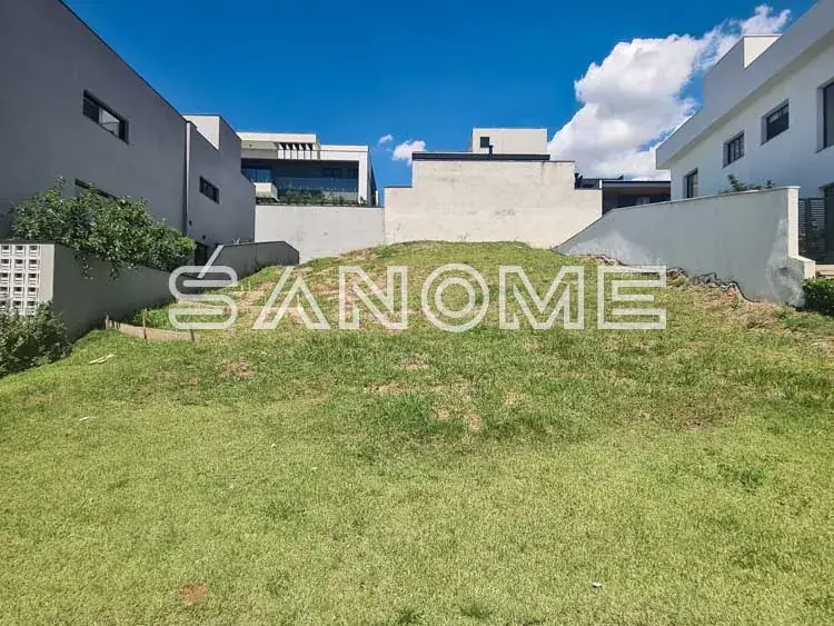 Terreno com grama e edificações ao fundo