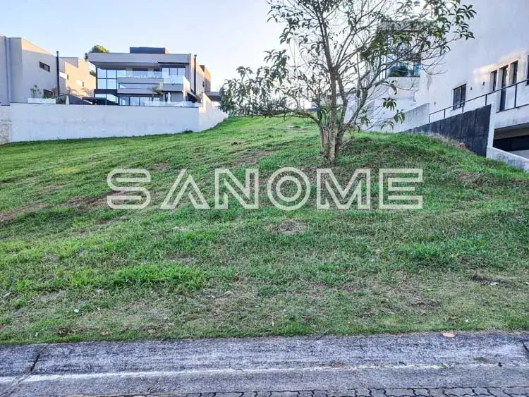 Terreno com grama e edificações ao fundo