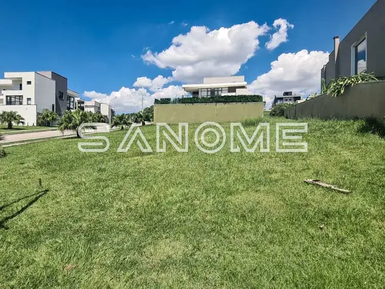 Terreno amplo com grama e residências ao fundo