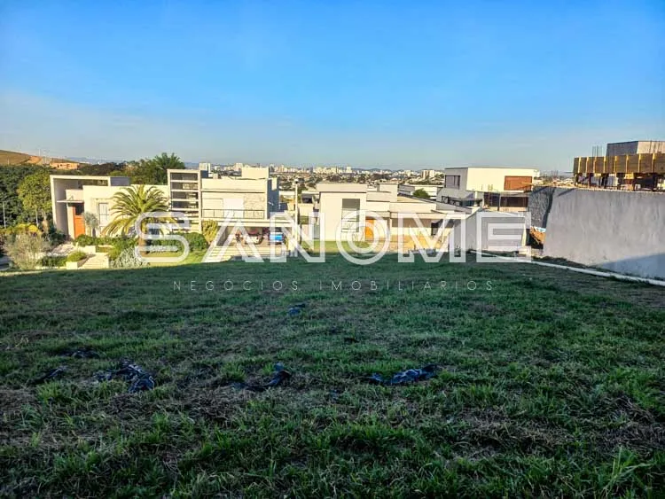 Terreno com grama e construções ao fundo