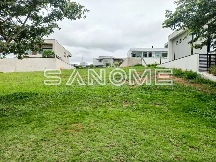 Terreno com grama e casarões ao fundo