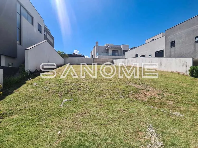 Terreno com grama e construções ao fundo