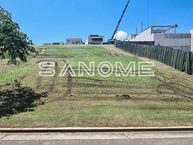 Terreno vazio com grama e construções ao fundo
