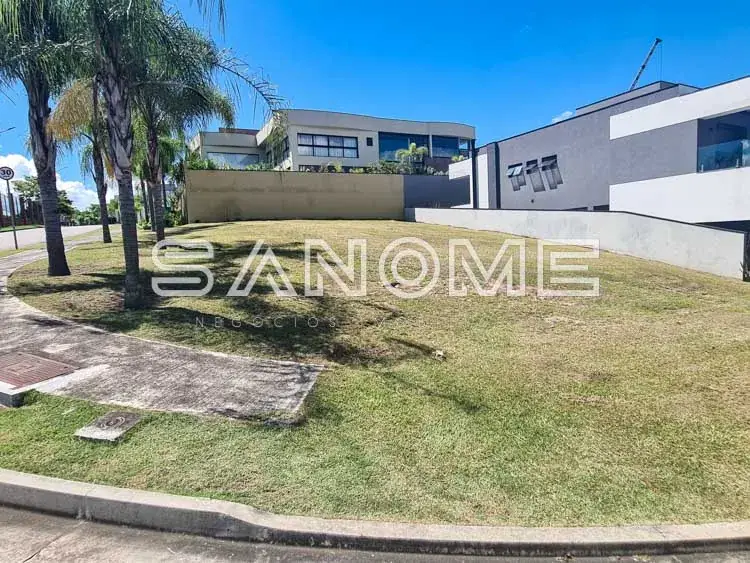 Terreno com grama e palmeiras ao fundo, edificação moderna