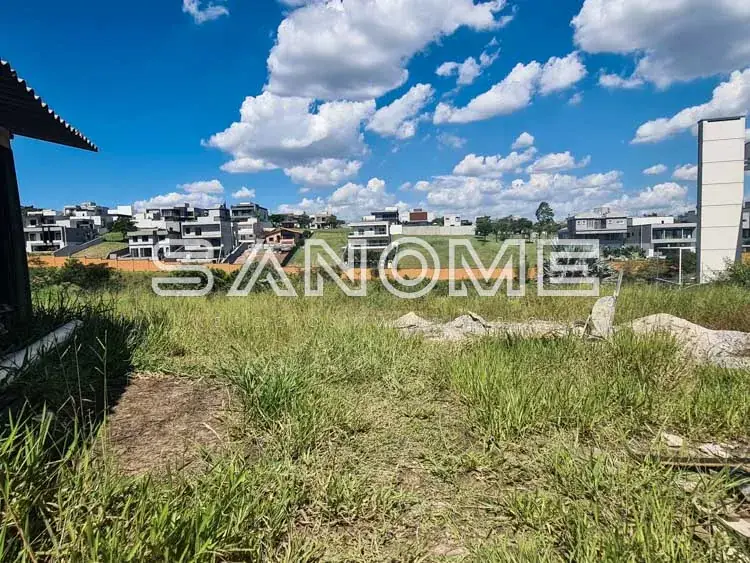 Terreno com grama e construções ao fundo
