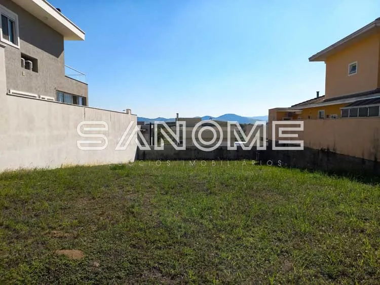 Terreno com grama e casarões ao fundo