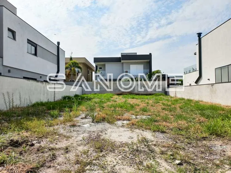 Terreno com casarões ao fundo e muro de concreto