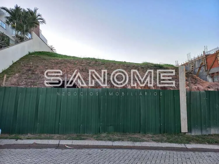 Terreno com placa de imobiliária e tapume verde