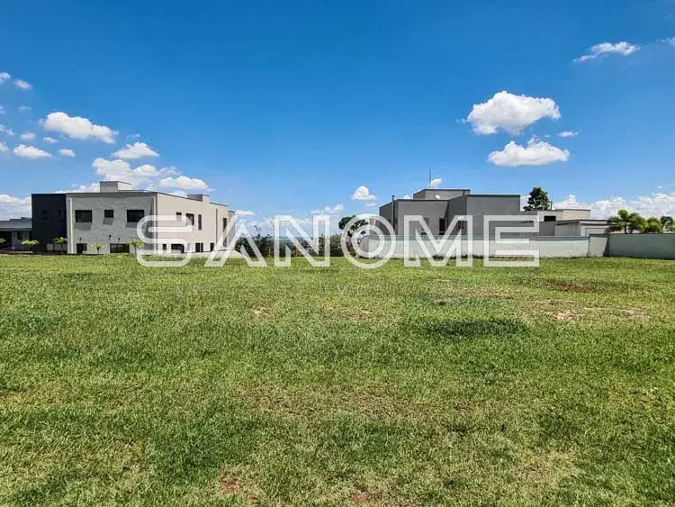 Terreno com casarões ao fundo e céu azul