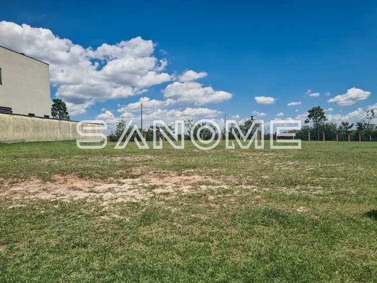 Terreno plano com grama e construção ao fundo
