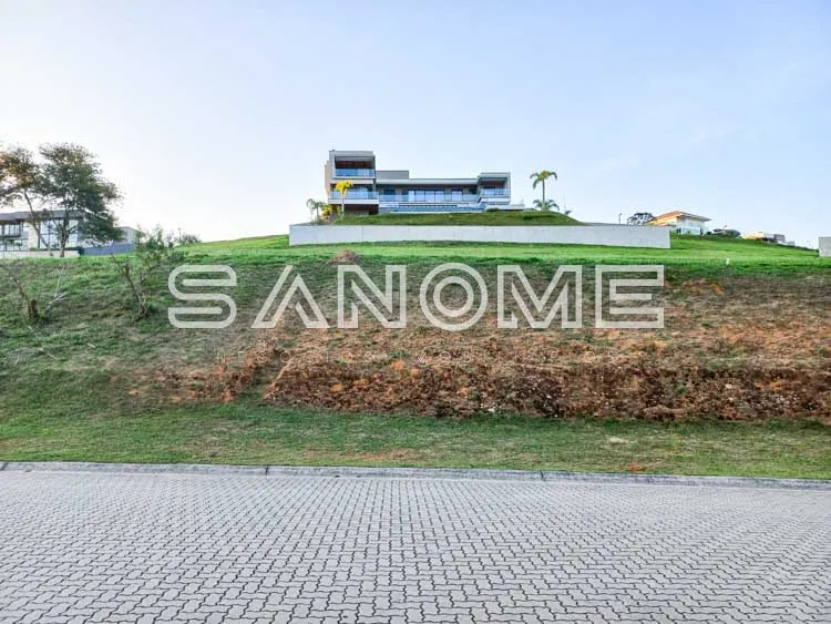 Terreno com placa indicativa e construção ao fundo