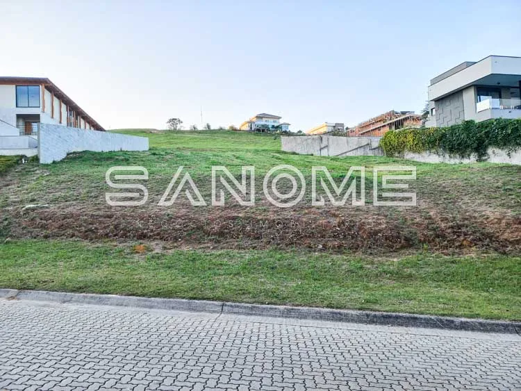 Terreno com grama e construções ao fundo