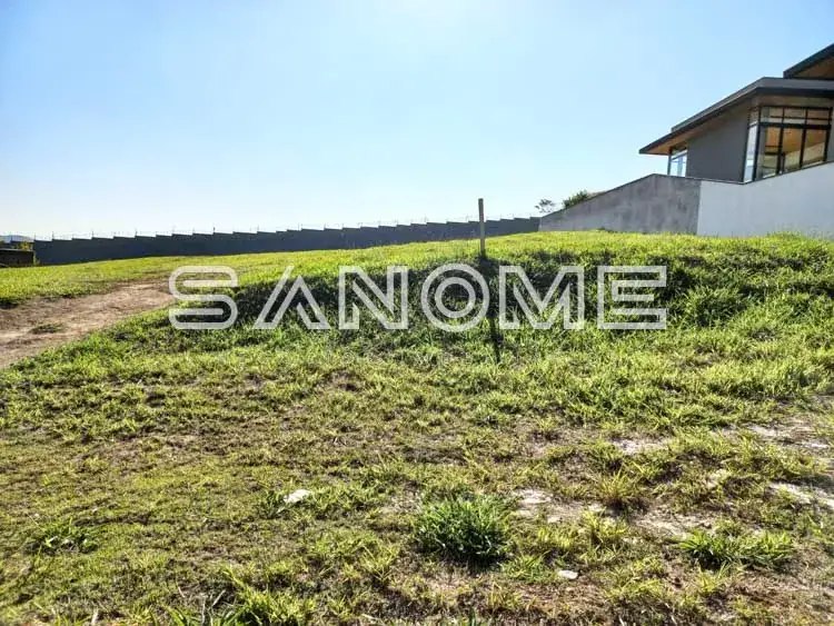 Terreno com casa ao fundo e placa de identificação