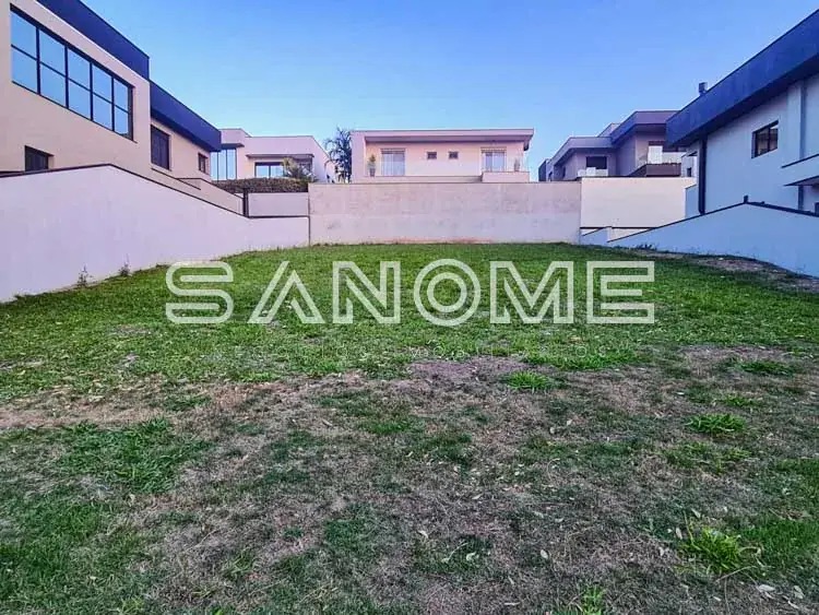 Terreno plano com grama e casarões ao fundo