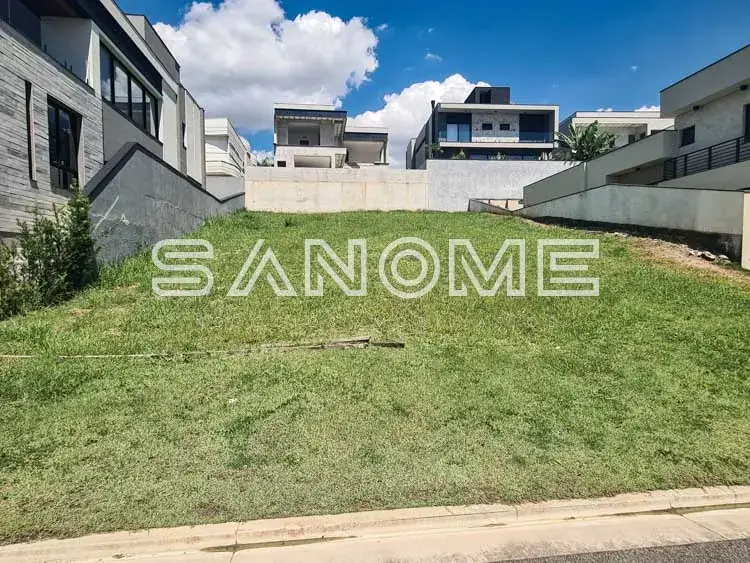 Terreno com grama e casarões ao fundo