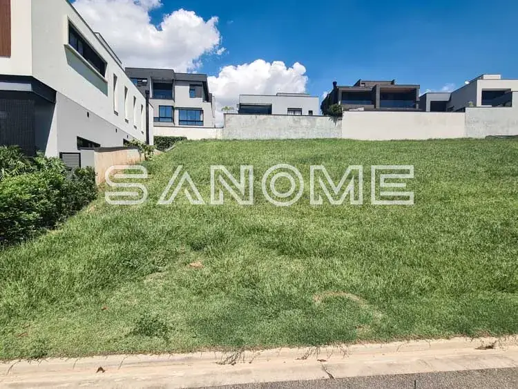 Terreno com grama e construções ao fundo