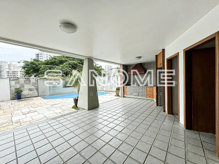 Área externa com piso em diagonal e piscina ao fundo