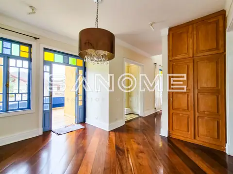 Sala com piso de madeira e porta de entrada com vitrais